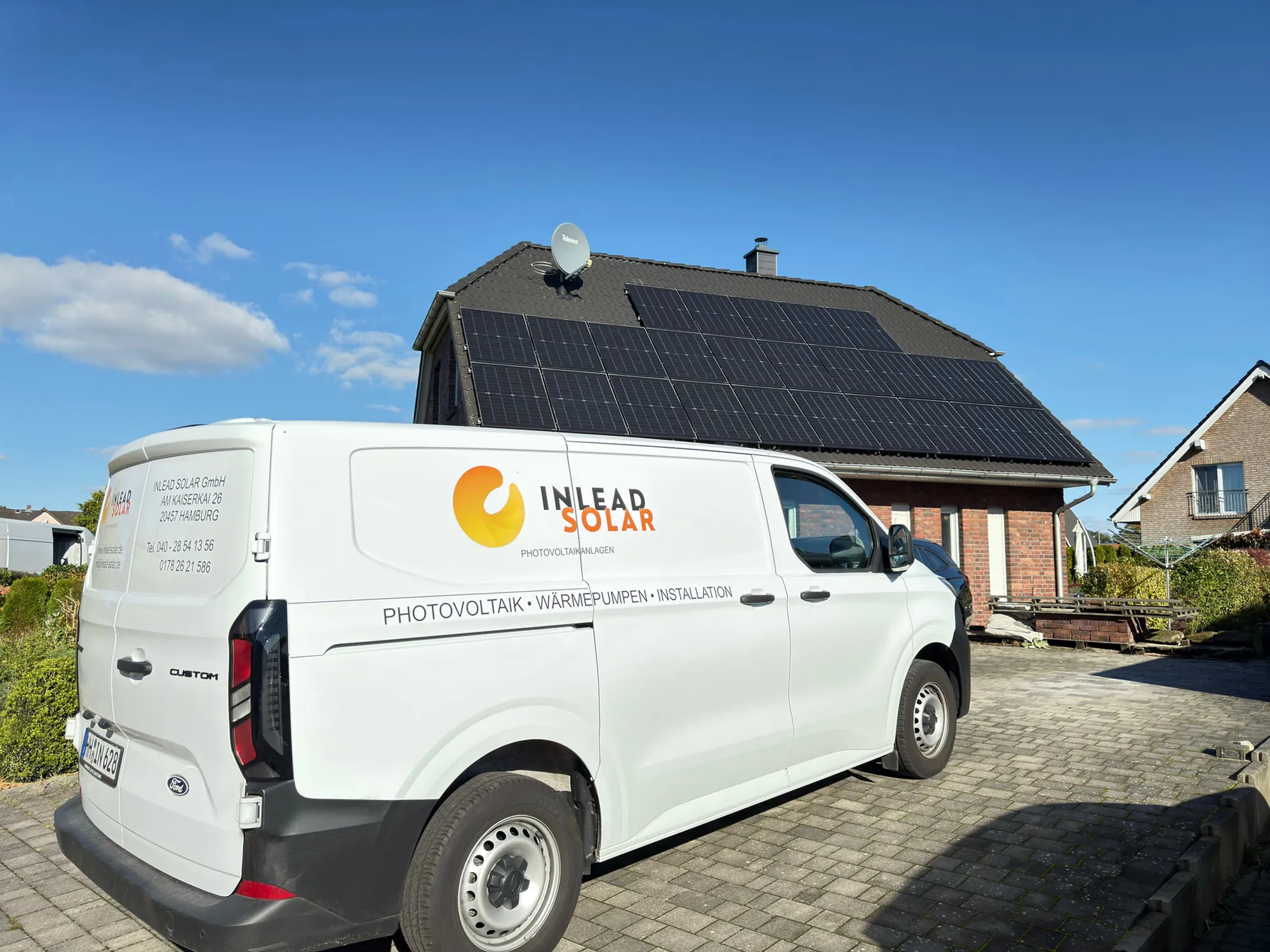 Transporter von Inlead Solar vor einem Haus mit Photovoltaikanlage